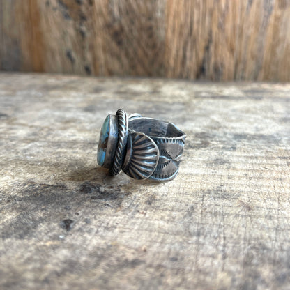 Silver ring with intricate designs on a wooden surface