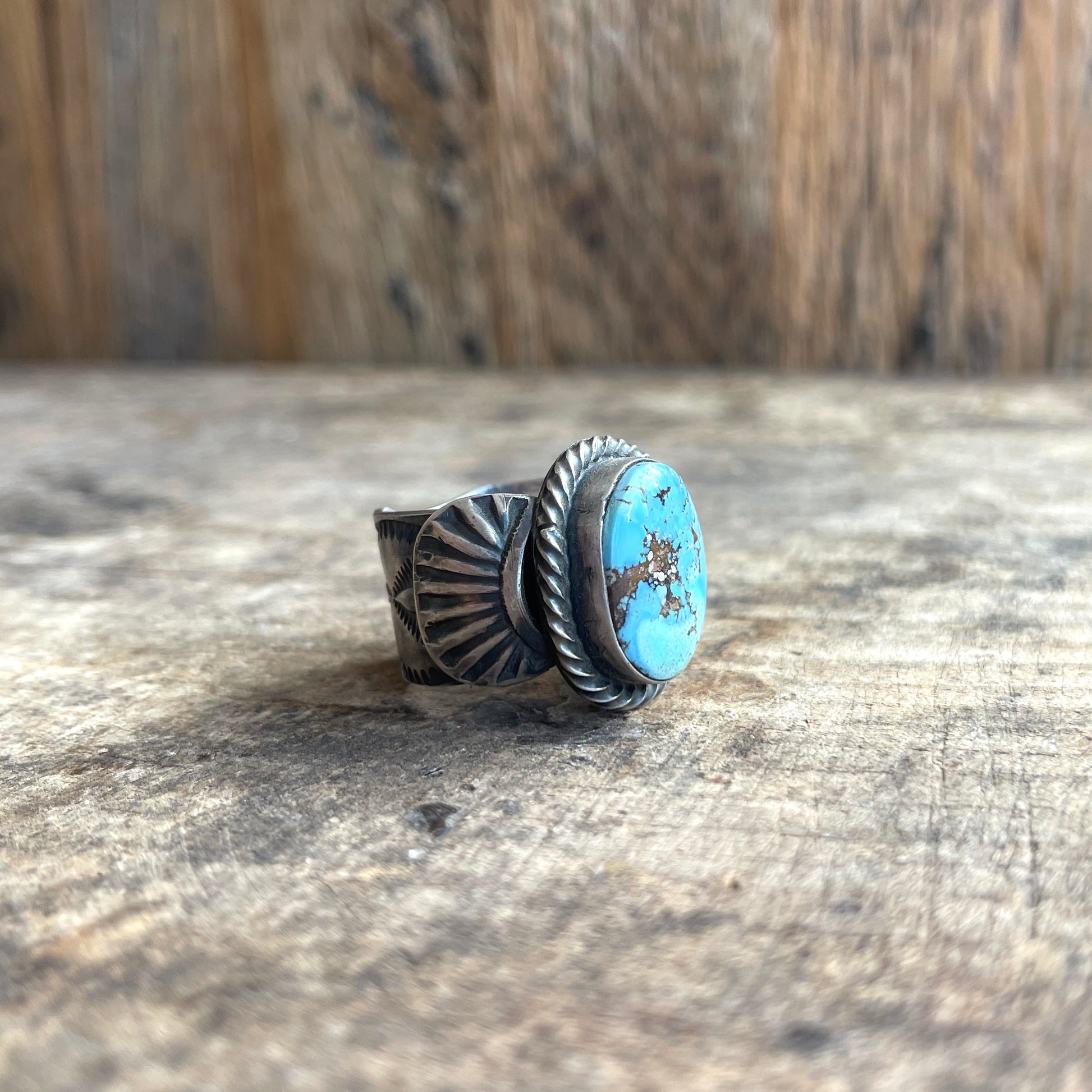 Silver ring with turquoise stone on a wooden surface