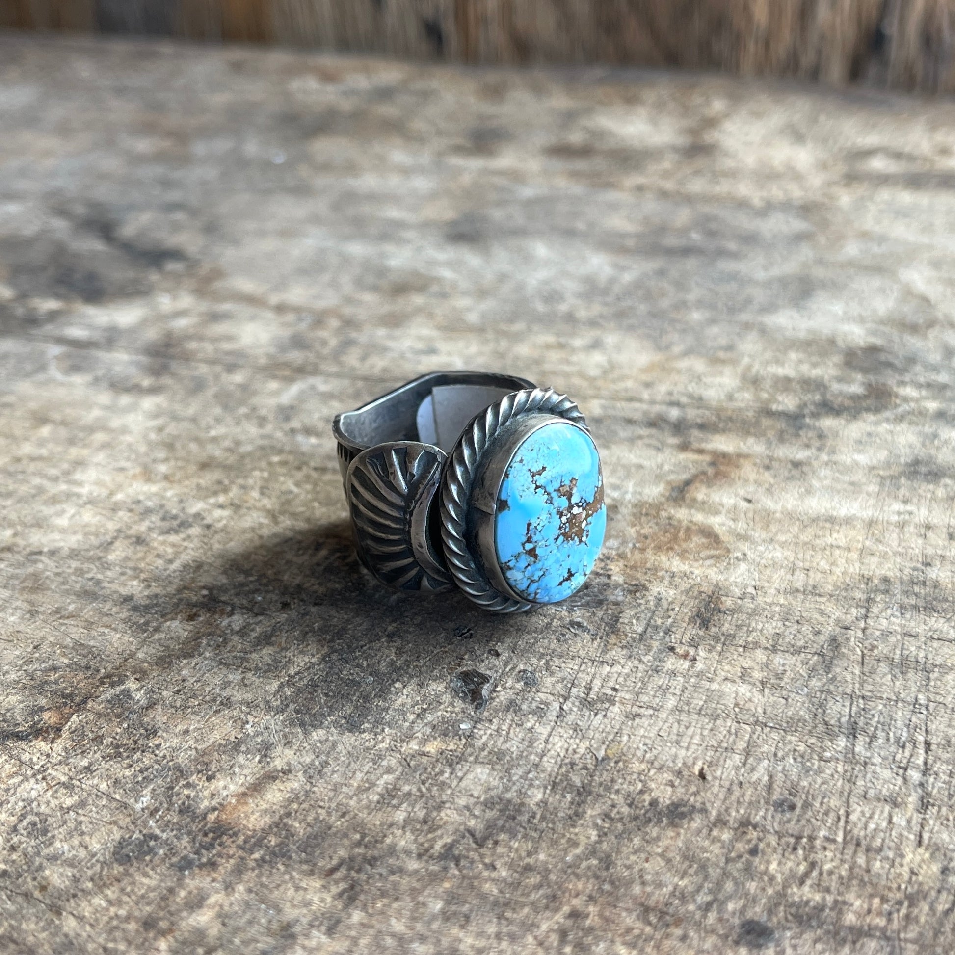 Turquoise stone ring with silver band on a wood surface