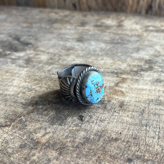 Turquoise stone ring with silver band on a wood surface