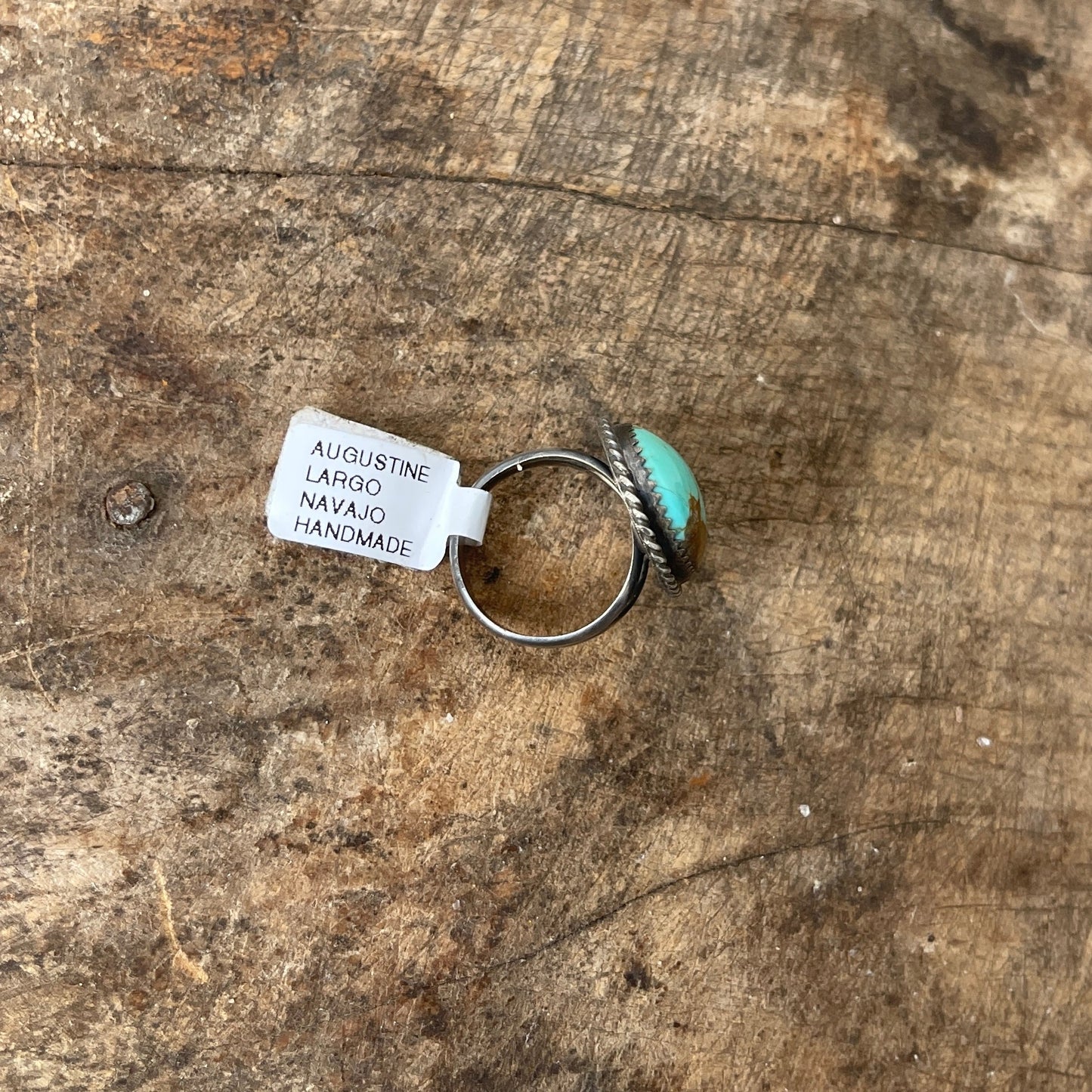 Turquoise ring with silver band on a wooden surface