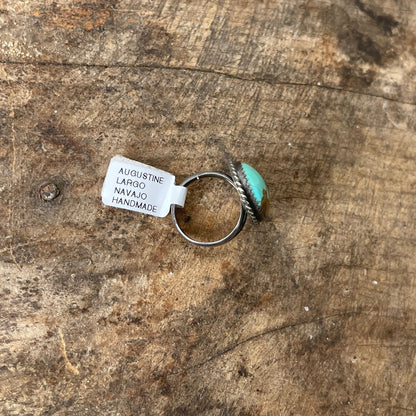 Turquoise ring with silver band on a wooden surface