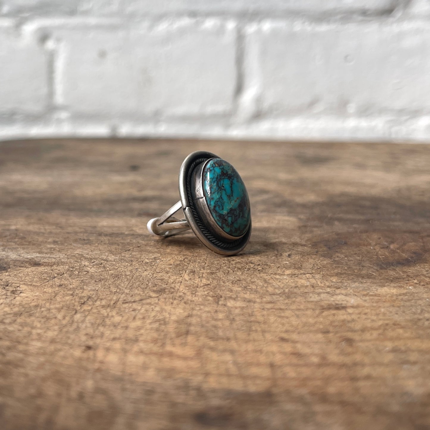 Silver ring with a blue stone on a wooden surface