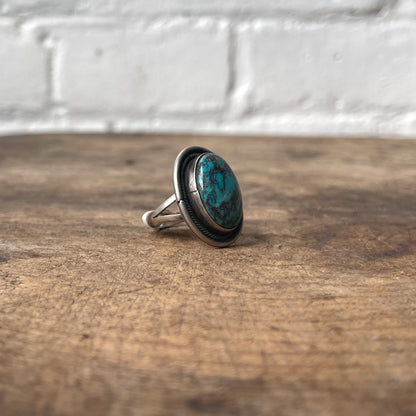Silver ring with a blue stone on a wooden surface