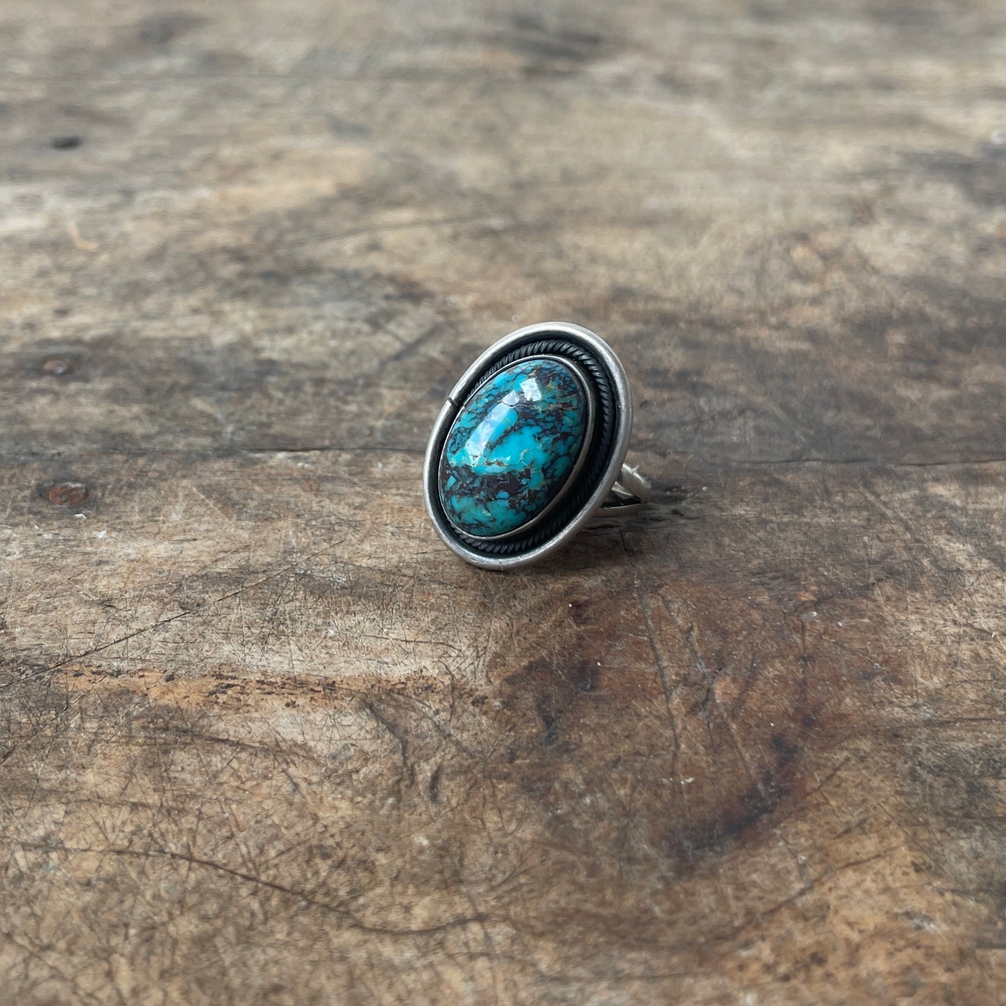 Silver ring with a turquoise stone on a wooden surface
