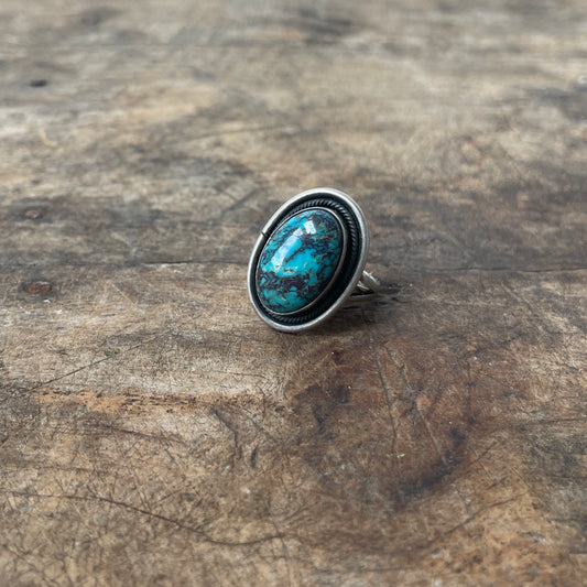 Silver ring with a turquoise stone on a wooden surface