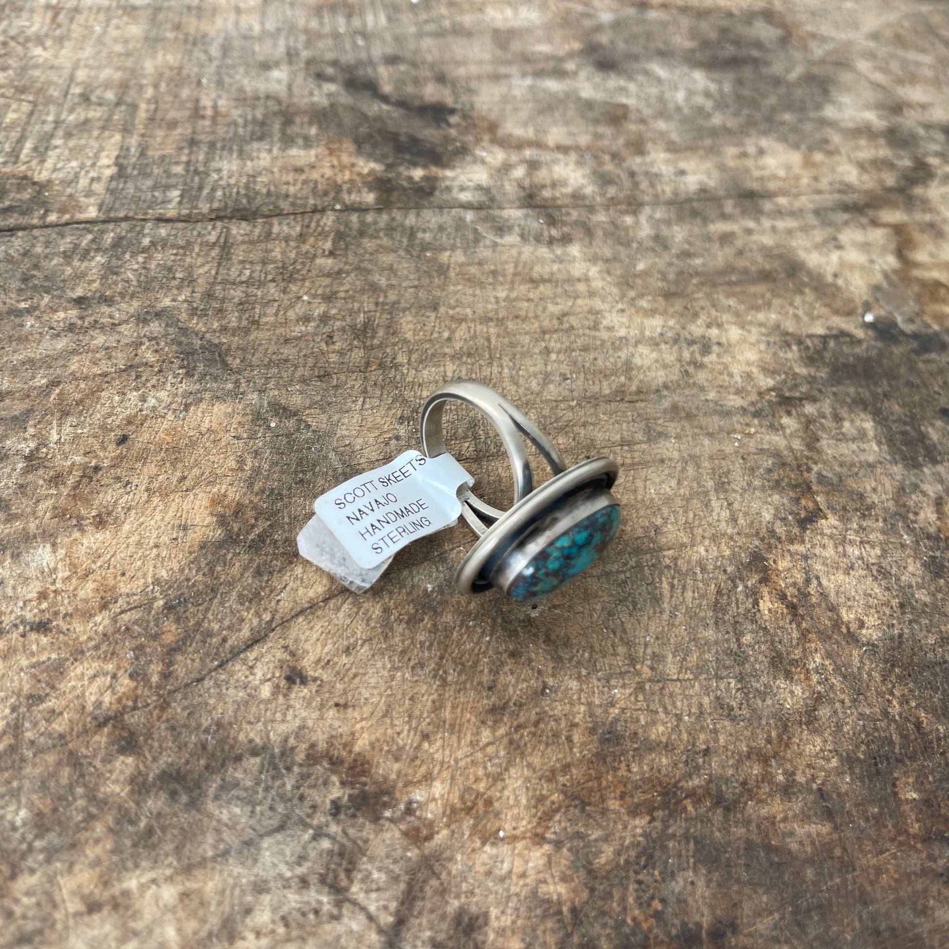 Silver ring with turquoise stone on a wooden surface