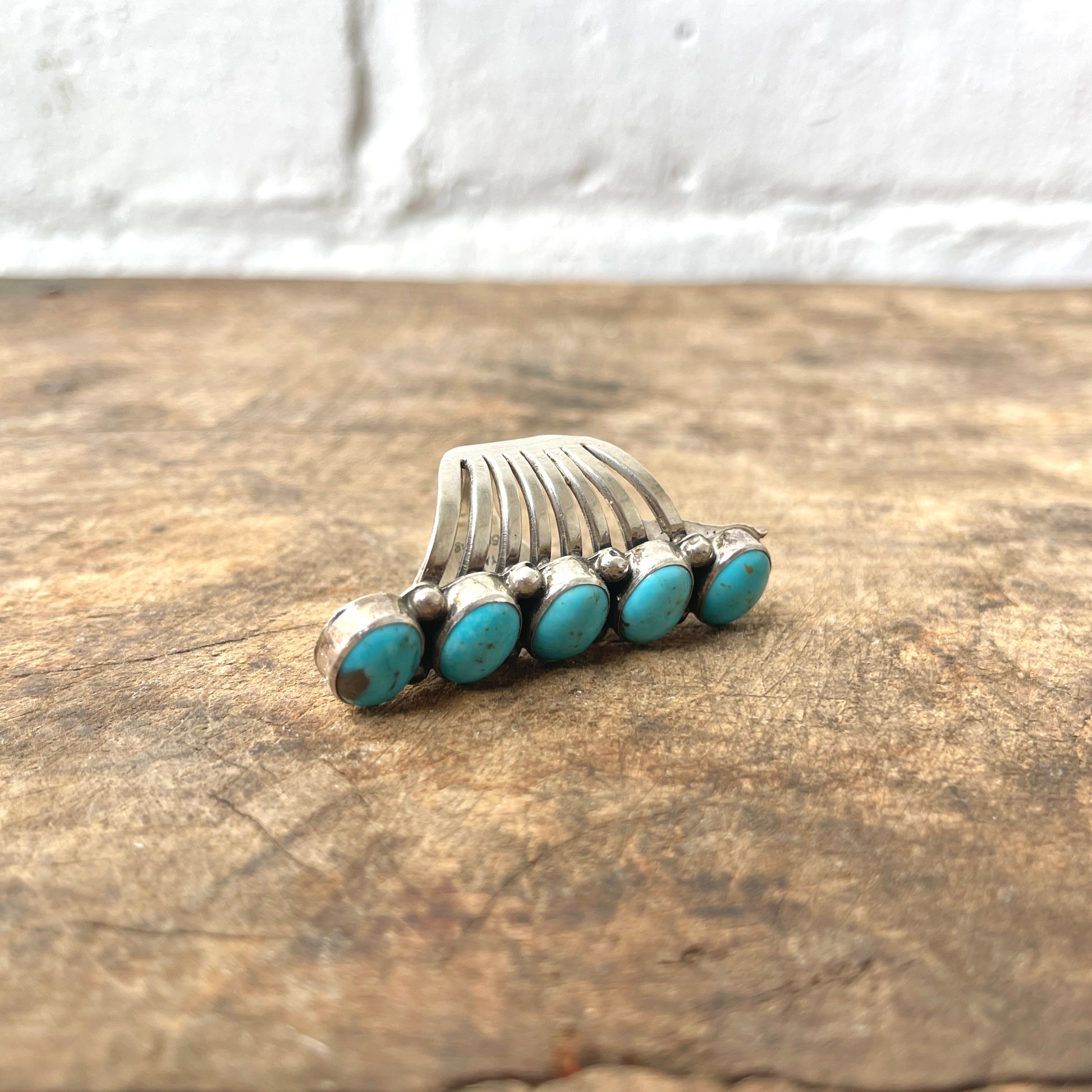 Silver ring with turquoise stones on a wooden surface