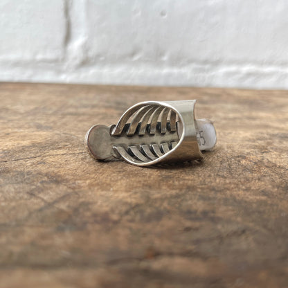 Silver ring on a wooden surface with a white tiled wall background