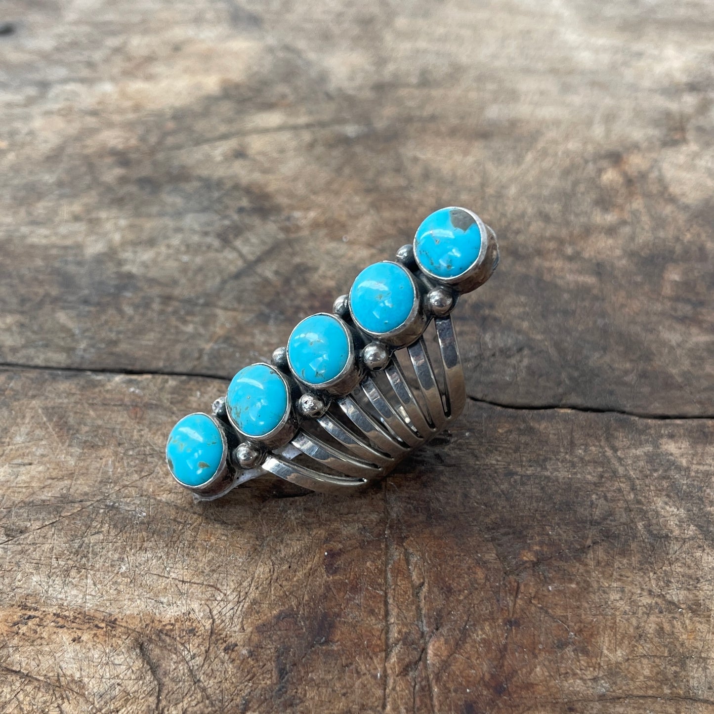 Silver ring with turquoise stones on a wooden surface