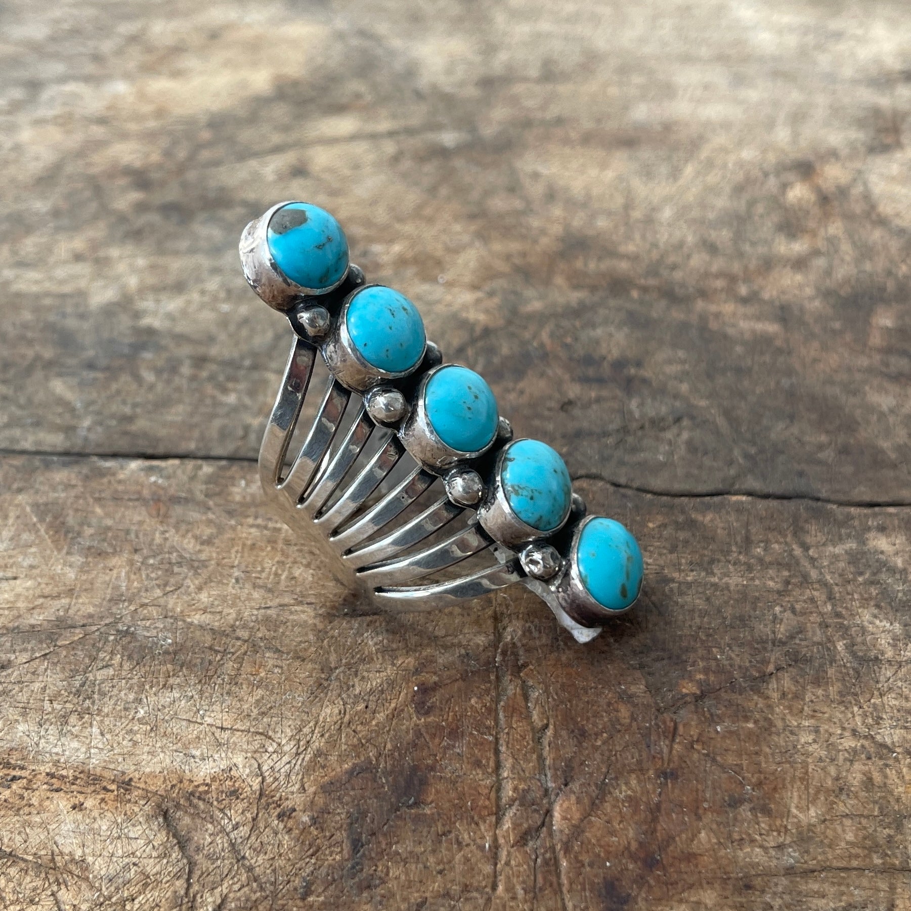 Silver ring with turquoise stones on a wooden surface