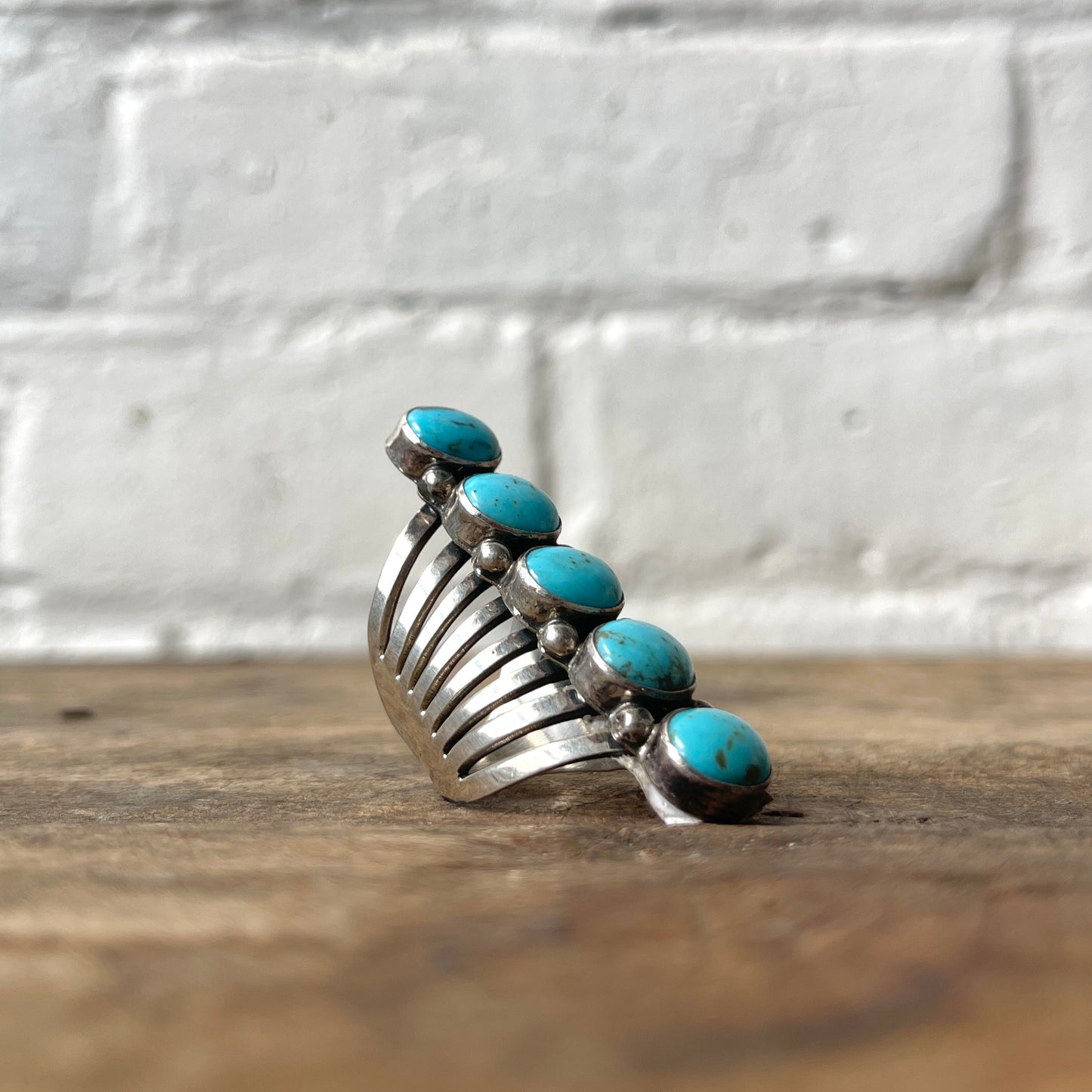Silver ring with turquoise stones on a wooden surface