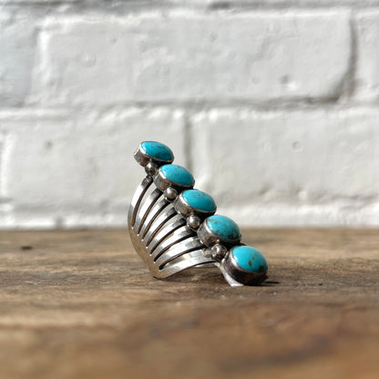 Silver ring with turquoise stones on a wooden surface