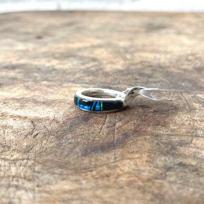 Silver ring with a colorful stone on a wooden surface