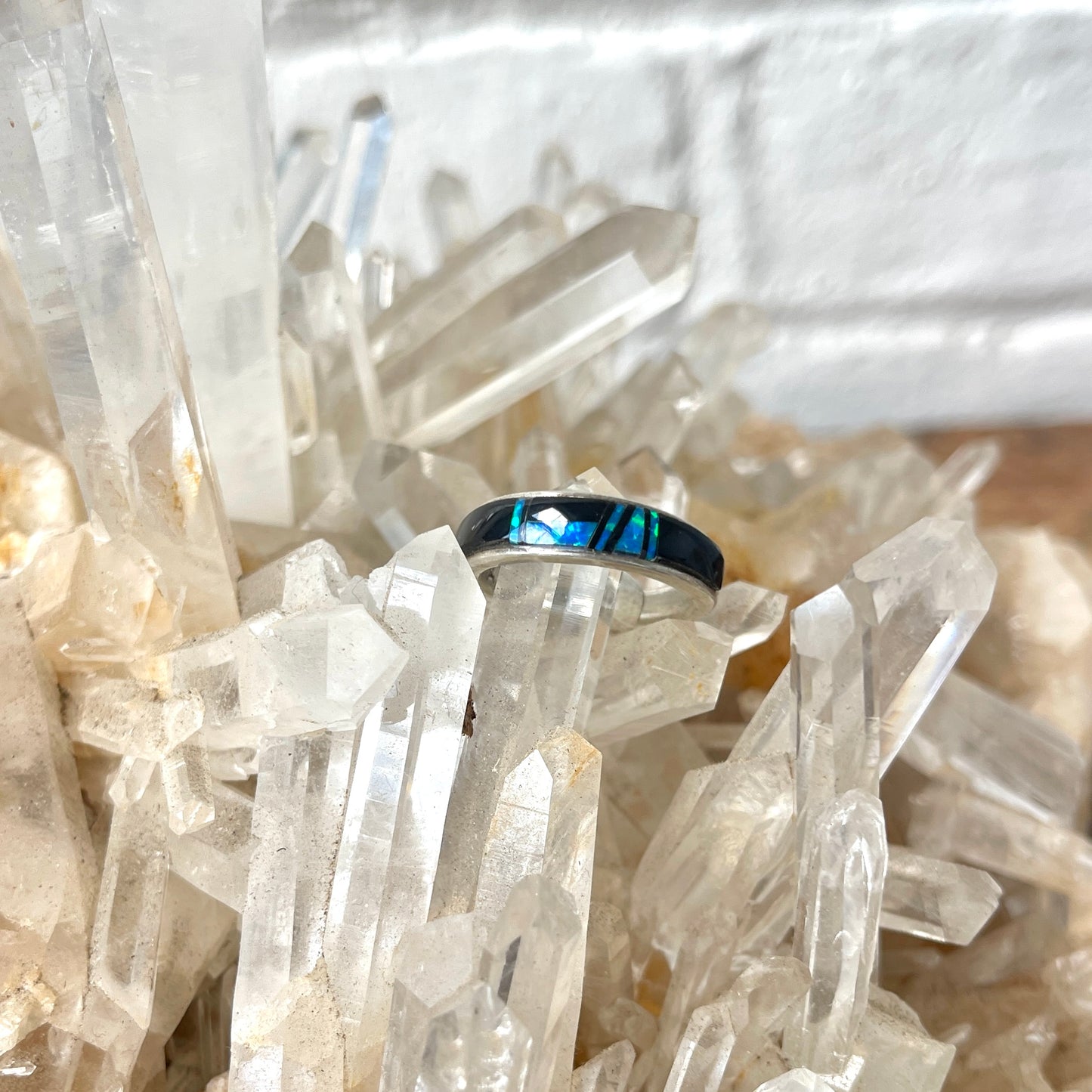 opal and onyx inlay ring on a bed of clear crystal crystals