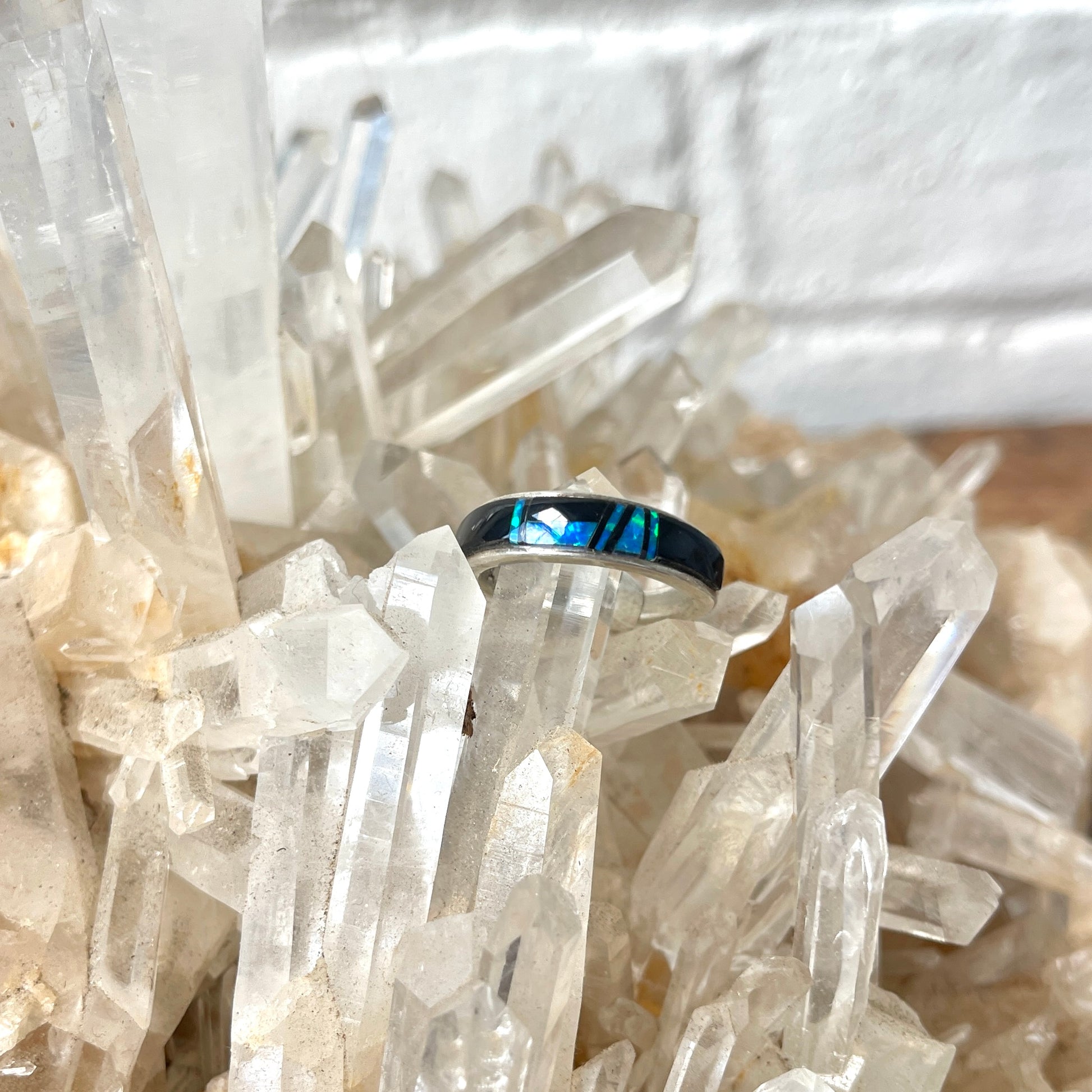 opal and onyx inlay ring on a bed of clear crystal crystals