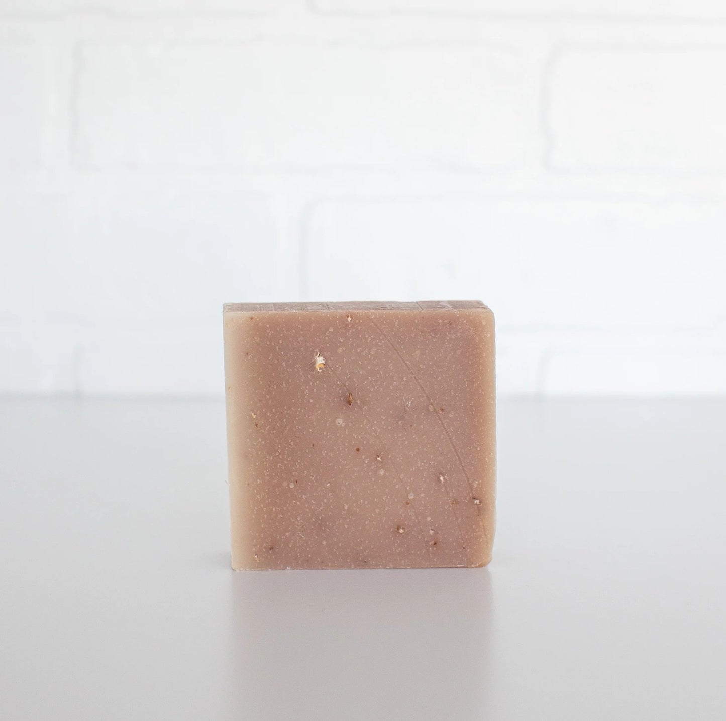 Square bar of soap with visible specks on a white background