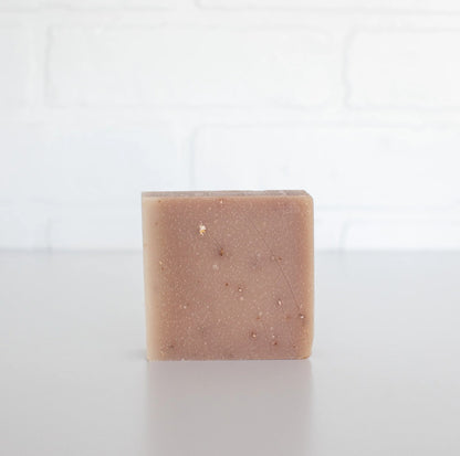 Square bar of soap with visible specks on a white background