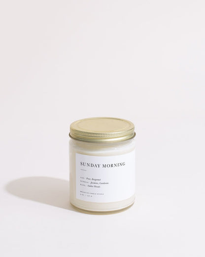Candle labeled 'Sunday Morning' with a gold lid on a white background