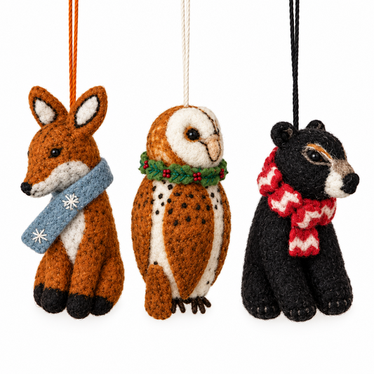Three small felt animal ornaments hanging against a plain white background: a brown fox with a blue scarf, a brown-and-white owl with a green scarf, and a black bear with a red-and-white scarf.