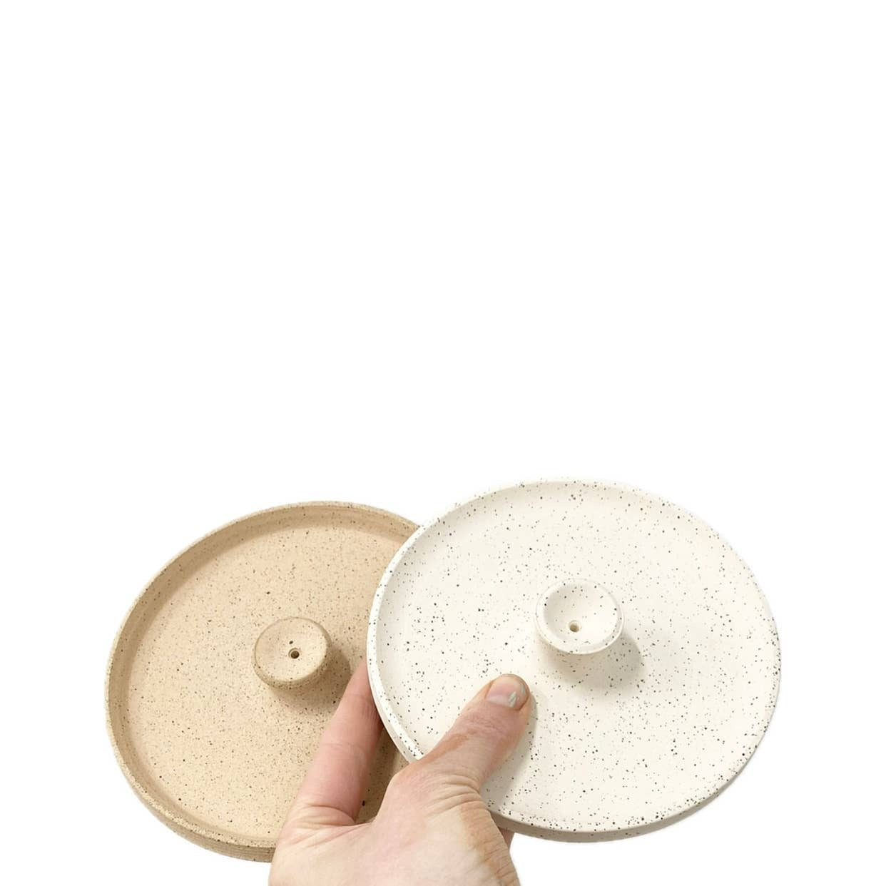 Hand holding a ceramic incense holders with a speckled pattern on a white background