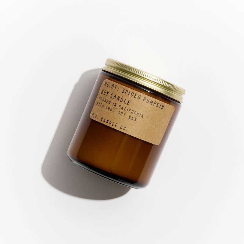 Amber glass candle with a gold lid and label on a white background