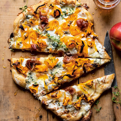 Cheesy pizza with slices cut on a wooden board, accompanied by an apple.