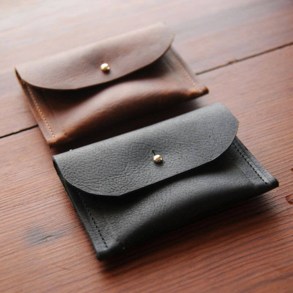 Two leather wallets, one black and one brown, on a wooden surface.