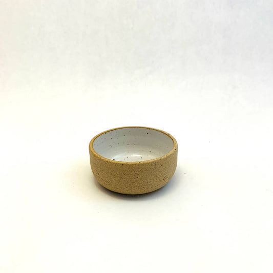 A small, beige, hand-made ceramic bowl on a white background.