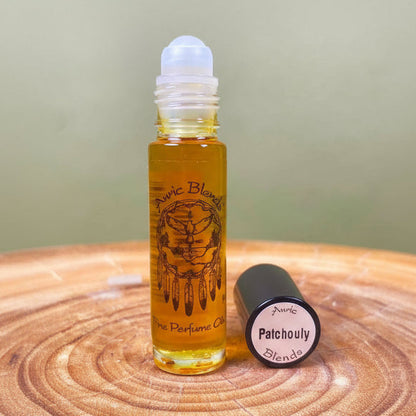 Roll-on bottle of Auric Blends Patchouly perfume oil on a wooden surface with a green background