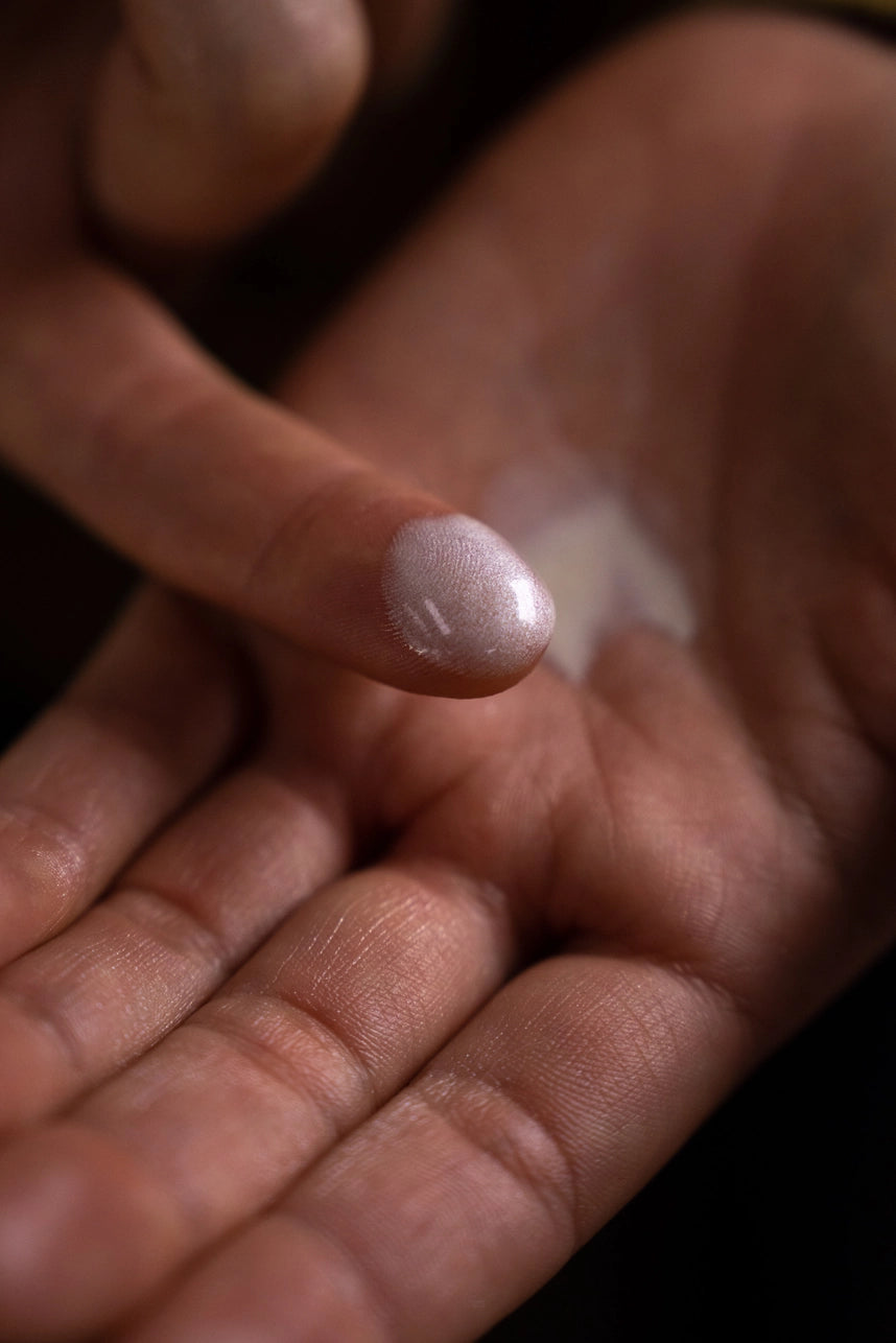 Hand holding a small pinkish stone against a blurred background