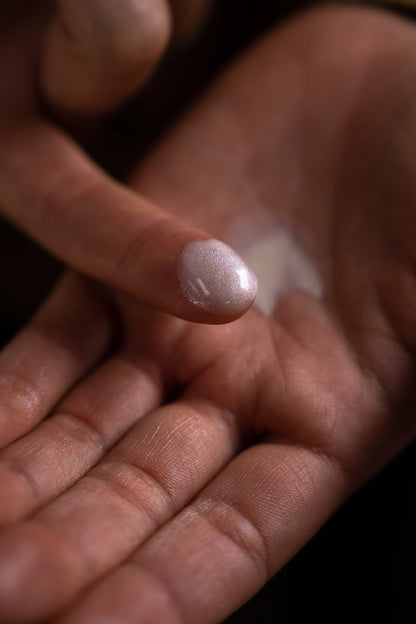 Hand holding a small pinkish stone against a blurred background