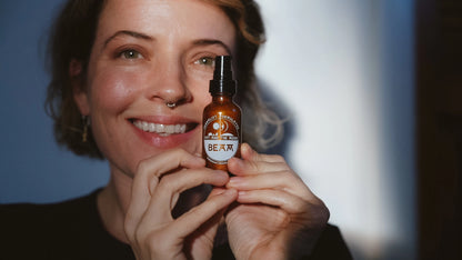 Person holding a bottle labeled 'Beam Oil' against a blurred background
