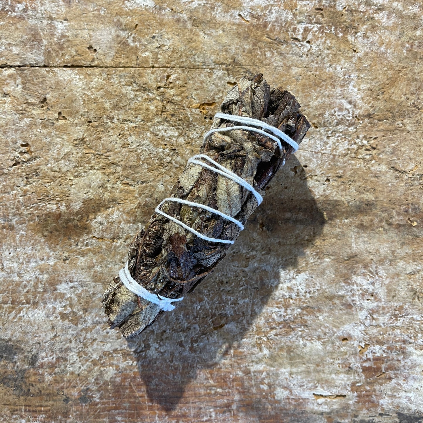 Bundled  black sage on a textured wooden surface