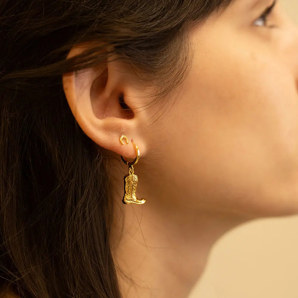 Close-up of a person wearing gold earrings with a blurred background