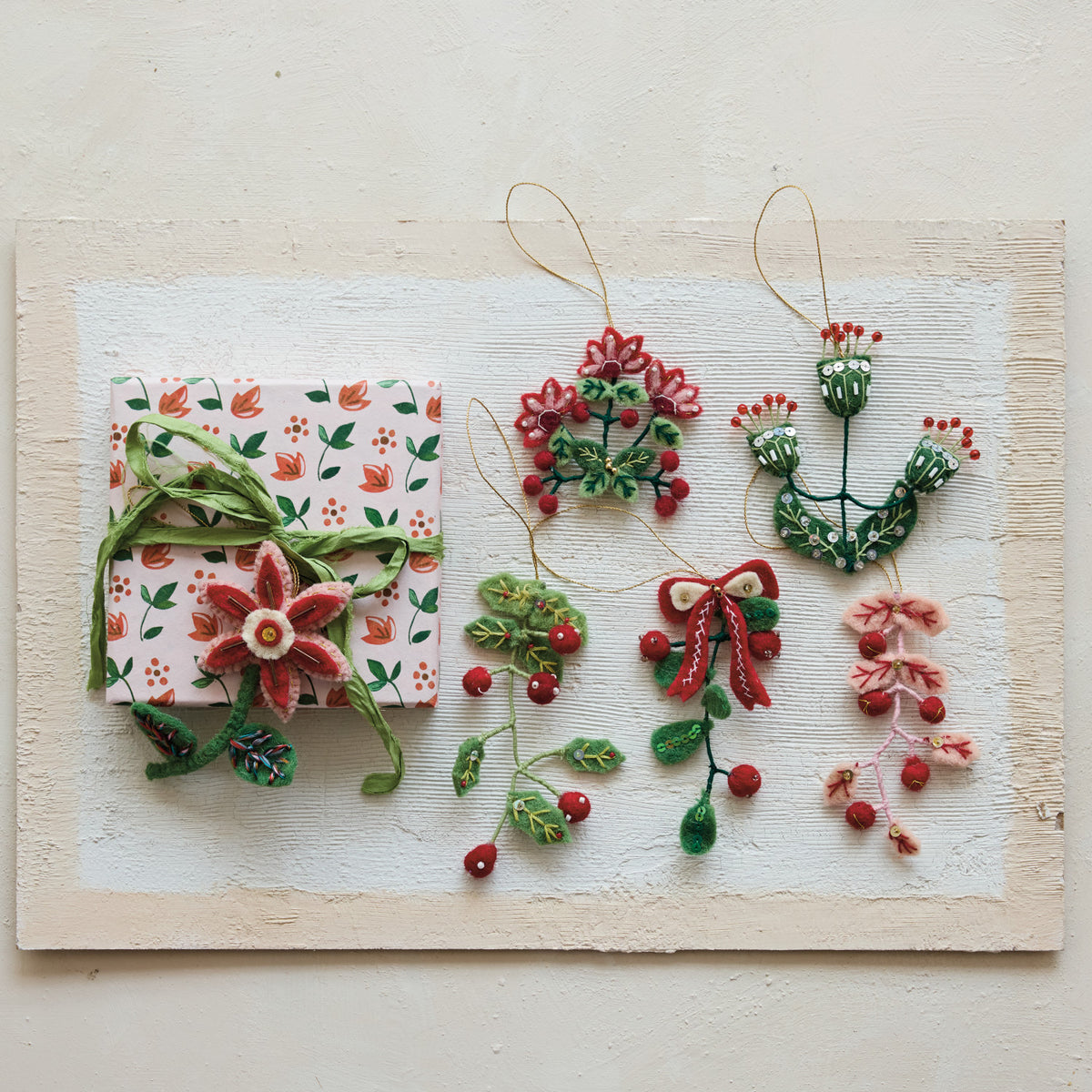 Decorative Christmas ornaments and gift box on a textured white surface
