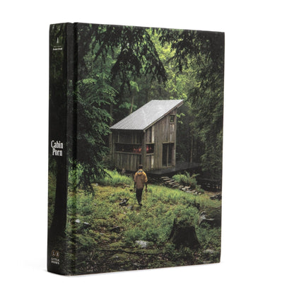 Book cover of 'Cabin Porn' with a cabin in the woods and a person walking towards it.