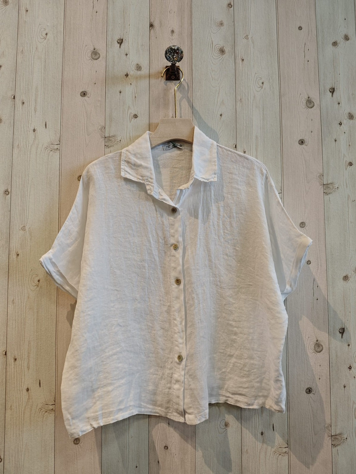White shirt on a hanger against a wooden wall