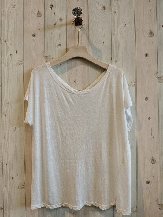 White t-shirt on a wooden hanger against a wooden wall.