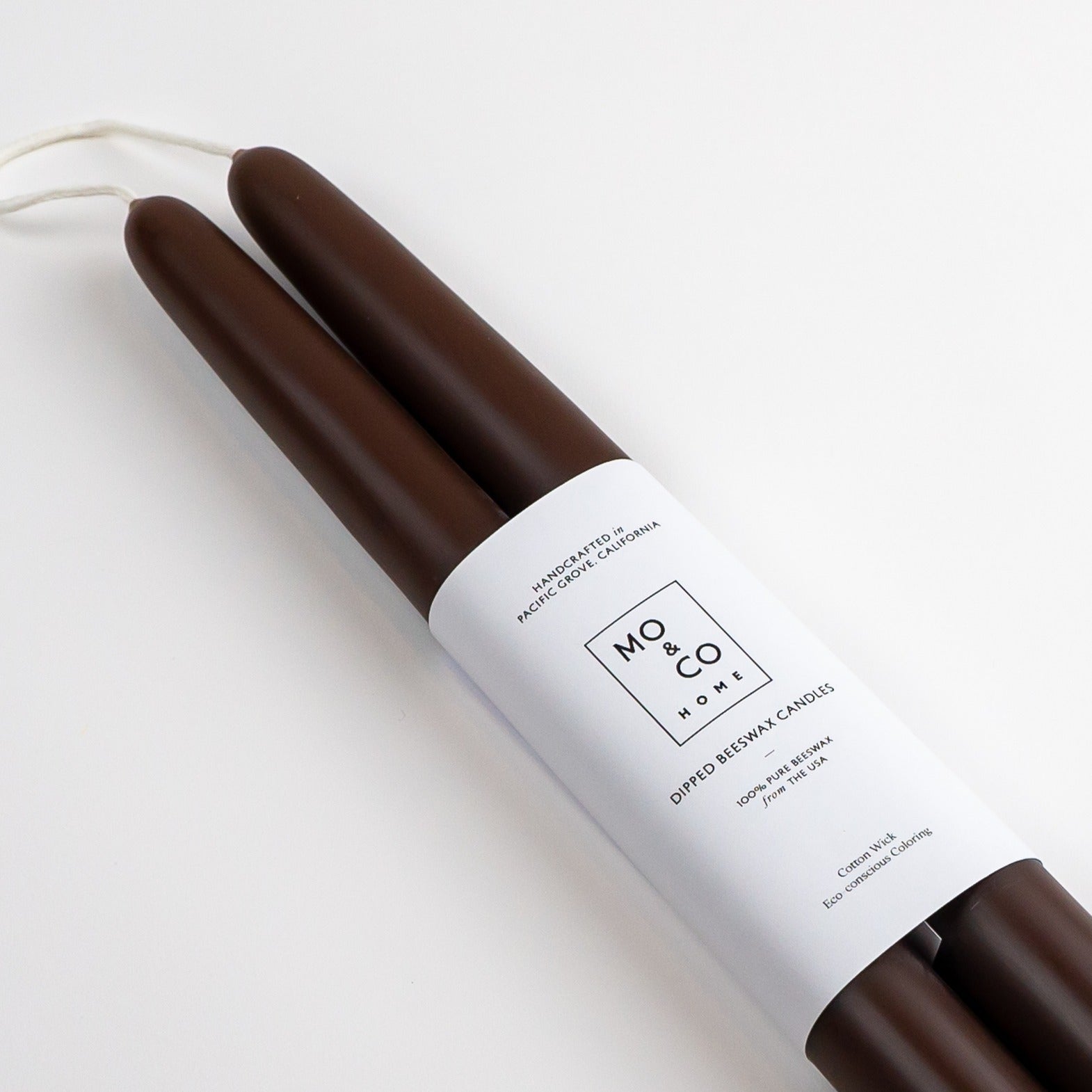 Two brown candles with a white label on a light gray background