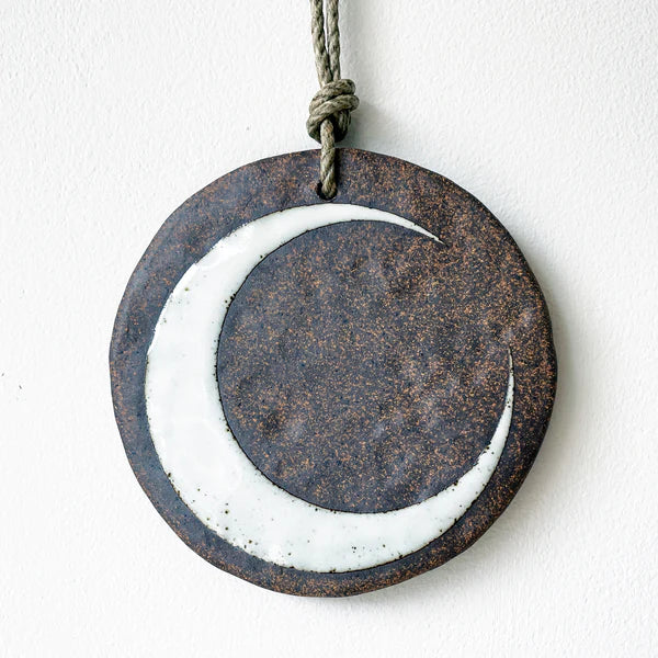 round ceramic wall ornament with brown and white crescent moon design