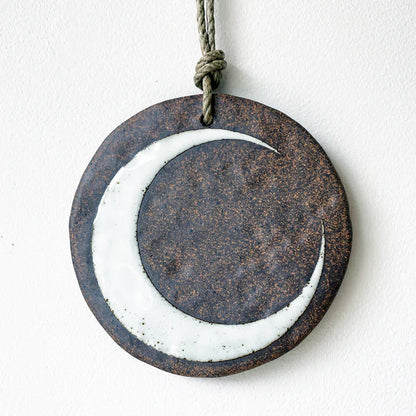 round ceramic wall ornament with brown and white crescent moon design