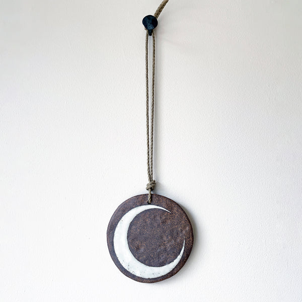 round ceramic wall ornament with brown and white crescent moon design