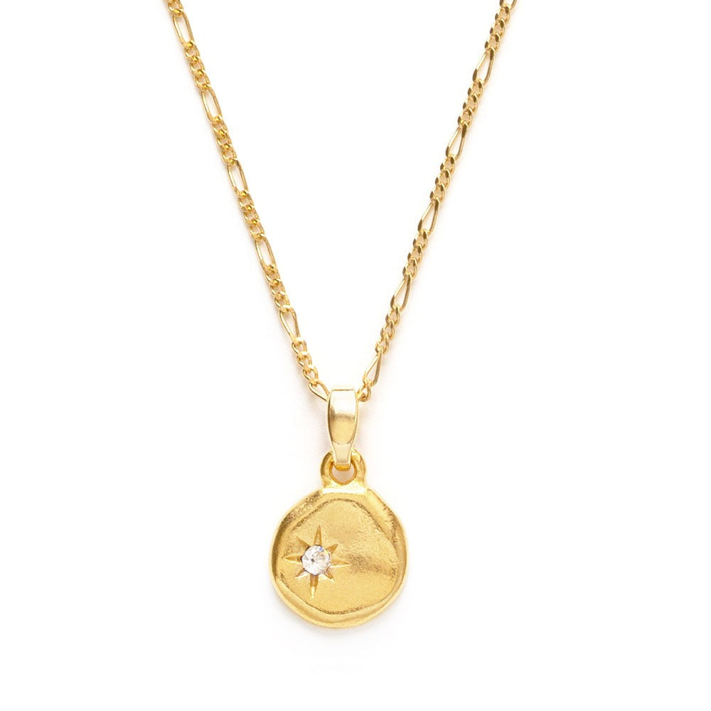 Gold necklace with a round pendant containing a clear crystal, on a white background