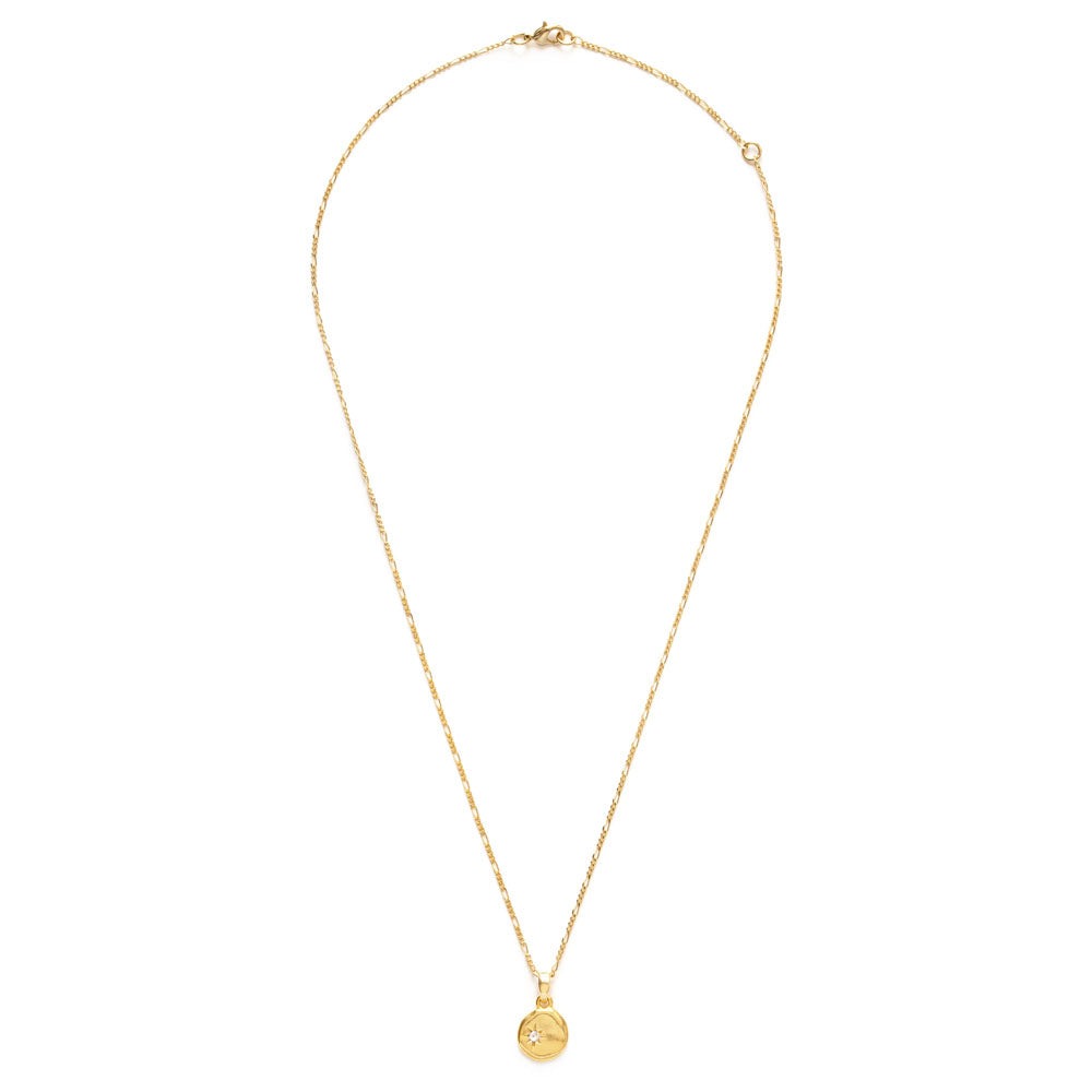 Gold necklace with a small pendant containing a small clear crystal, on a white background