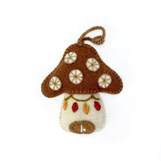 Felted mushroom ornament with brown cap and white spots on a white background