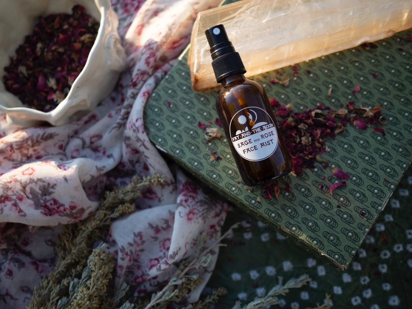 Brown glass bottle with a label on a green textured surface with dried flowers and a floral cloth.
