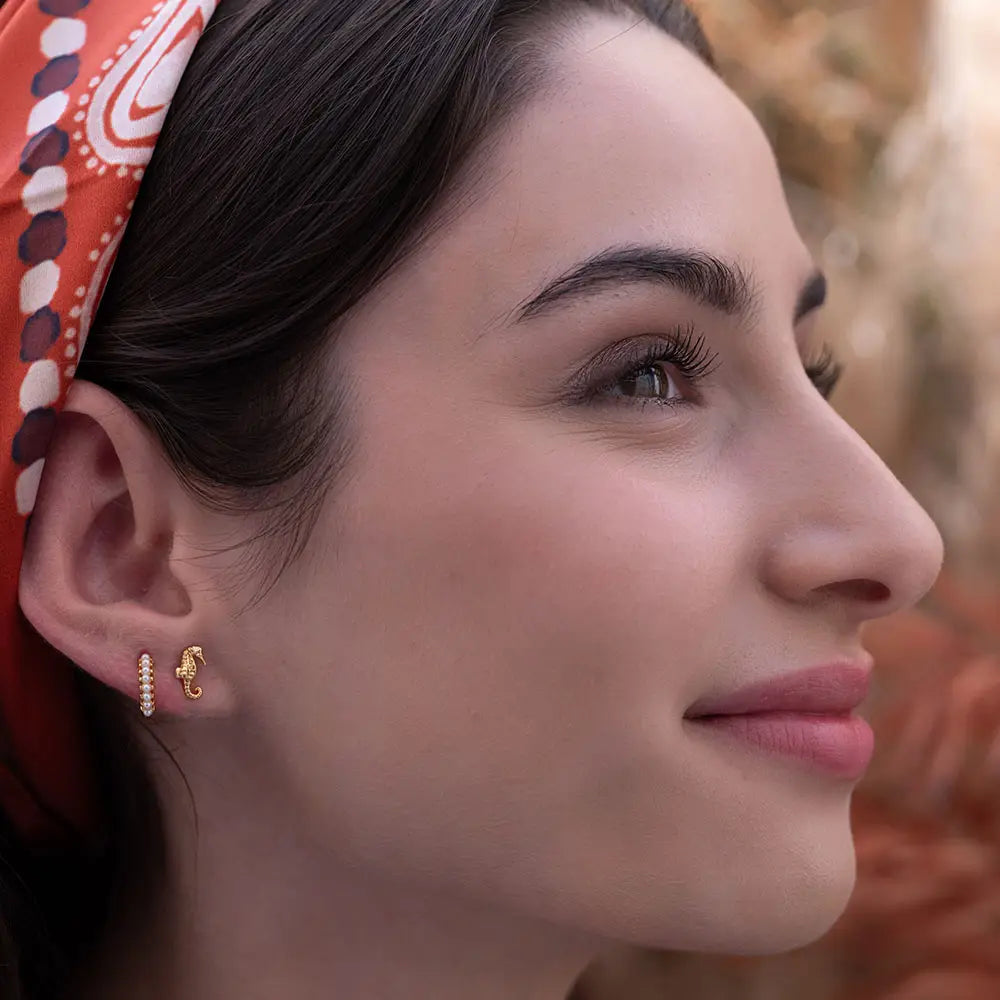Close-up of a woman wearing gold earrings with a blurred background