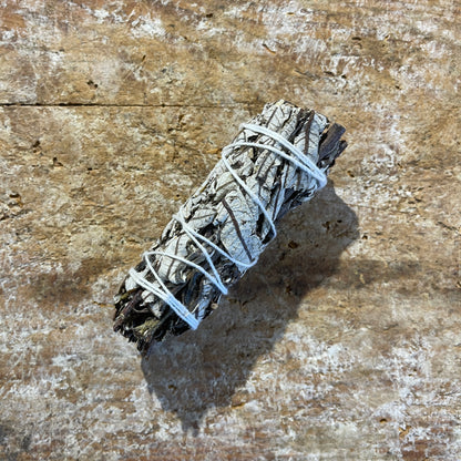 Bundled yerba santa and sage on a textured wooden surface